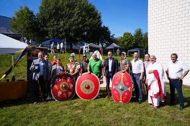 Gruppe von Personen in historischen Kostümen mit Schilden im Freien
