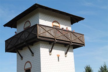 Holzturm mit Aussichtsplattform und Besucher im Freien