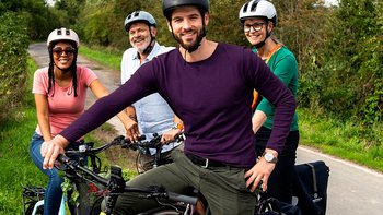 Vier Personen mit Fahrrädern auf einem malerischen Weg im Freien