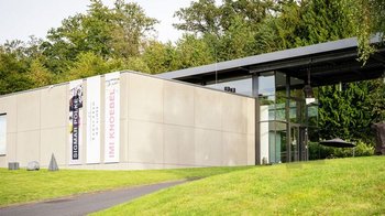 Architektur einer Galerie umgeben von Bäumen und Rasenflächen