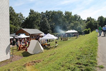 Outdoor-Veranstaltung mit Zelten, Menschen und Bäume im Hintergrund