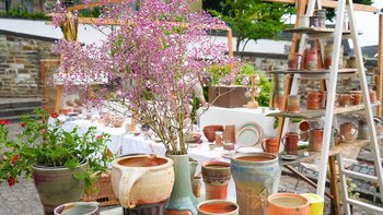 Verschiedene Töpferwaren und Blumen auf einem Marktstand im Freien